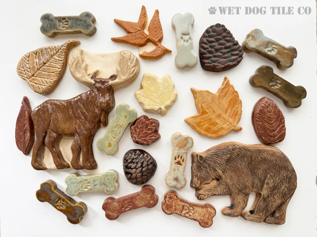 handmade glazed ceramic tiles shaped like leaves, bear, moose, pine cones, and dog bones