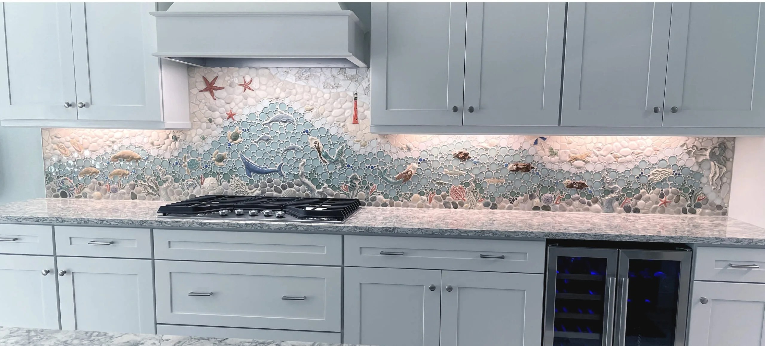 mosaic backsplash tiles featuring whales and mermaids. The palette of the mosaic made color selection for counters and cabinets very easy